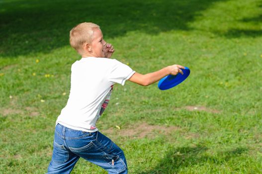 Little boy playing frisbee on green grass