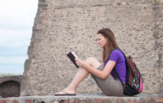 Teen girl reading the Bible sitting outdoors