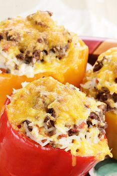 Three baked bell  stuffed peppers with beef, rice, vegetables and cheese.
