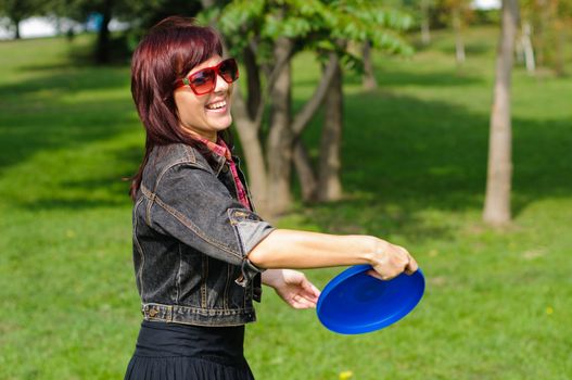 Young woman having fun with frisbee in the parkin sunny summer day.