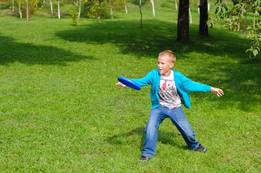 Little boy playing frisbee on green grass