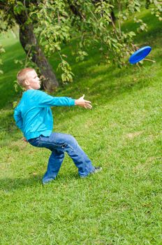 Little boy playing frisbee on green grass