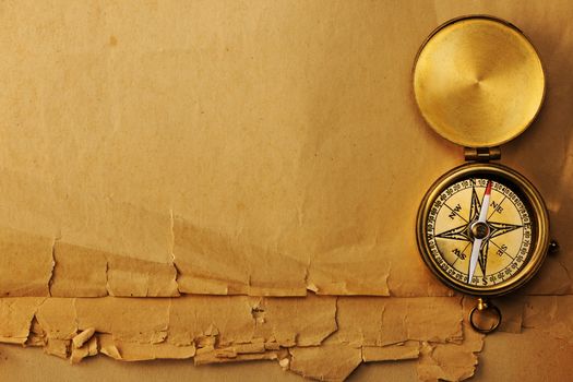 Antique brass compass over old paper background