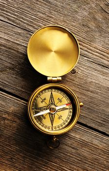 Antique brass compass over wooden background