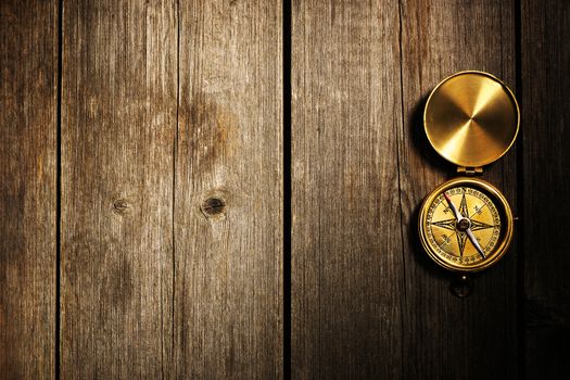 Antique brass compass over wooden background