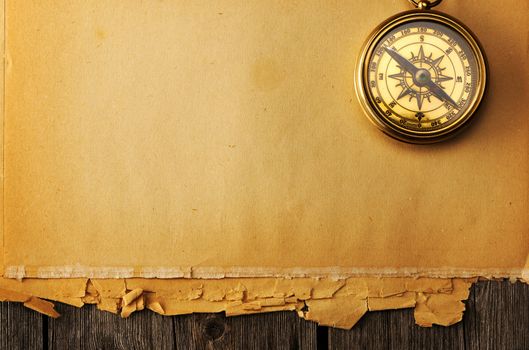 Antique brass compass over old paper background