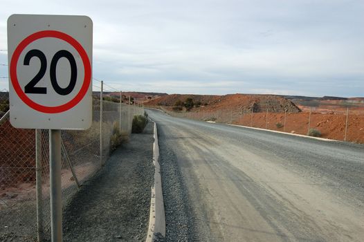 Speed limit sign at gravel road near gold mine