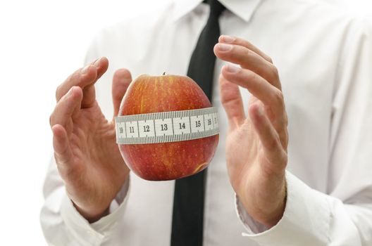 Male hands around apple wrapped with measuring tape. Concept of healthy and responsible dieting.