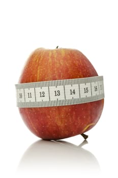 Measuring tape wrapped around apple. Concept of diet and healthy eating.