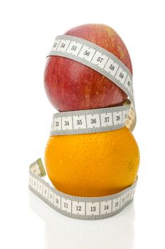 Apple on top of orange wrapped with measuring tape. Weight loss concept.