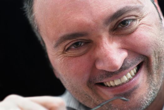 Close up portrait of smiling man on black background