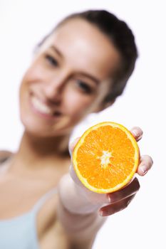 Beauty shot of a young woman with orange half on white background, focus on orange