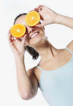 Funny girl portrait, holding oranges over eyes, diet concept