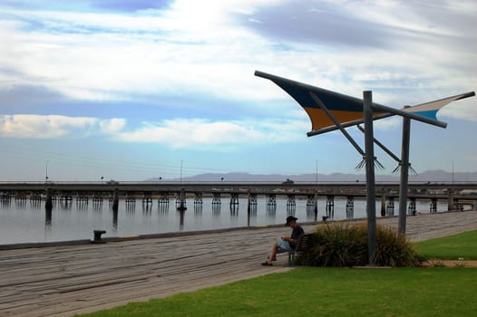 Man is sitting on the bench in rest area, Port Ogasta, South Australia