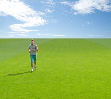 Sporty young man running on green field, under blue sky.
