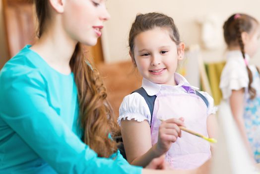 girl in the school, near the teacher and other children