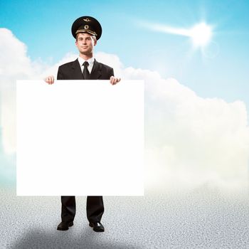 pilot in the form of holding an empty billboard on the background of sky with clouds, place for text