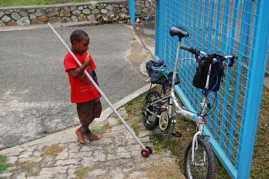 Boy looks on folding bicycle, Port Moresby, Papua New Guinea