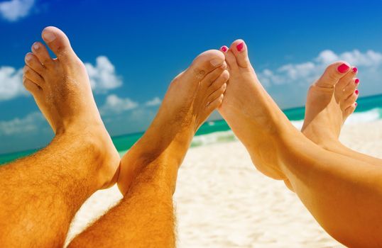 picture of male and female legs over tropical beach background