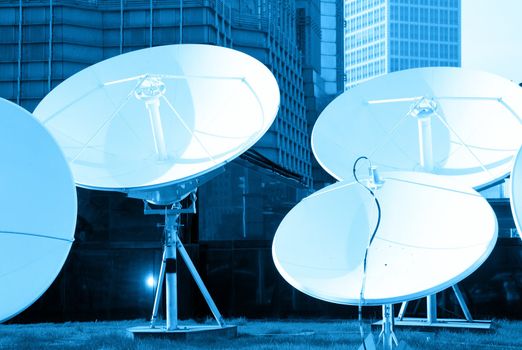 blue toned picture of parabolic satellite dish space technology receivers