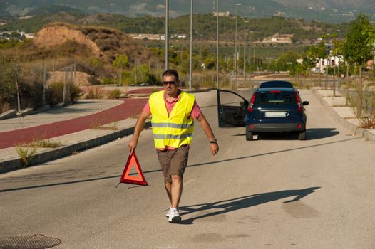 Guy carrying a triangle to warn of his breakdown