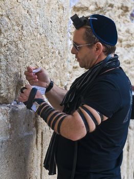JERUSALEM - NOVEMBER 03 2011 : A jewish man lay tefillin in The western wall an Important Jewish religious site located in the Old City of Jerusalem , Israel