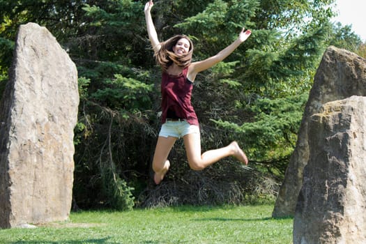 A pretty girl jumps for joy in a park.