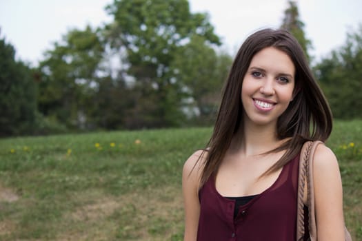 A pretty girl smiles happily in the park.