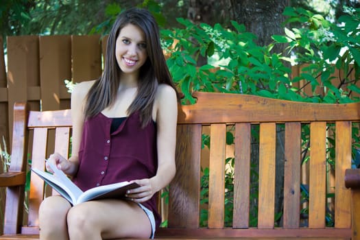 A pretty girl reads a book in her backyard.