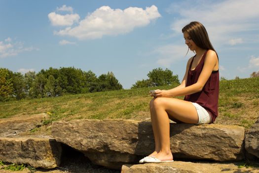 Pretty girl texting in the park - copyspace