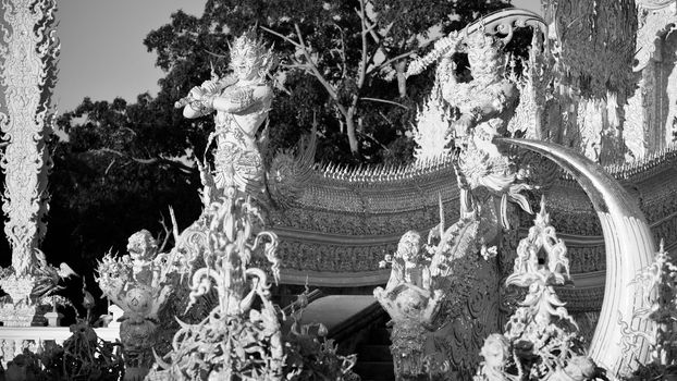 Statues of mythological guardians in white temple Wat Rong Khun.  Wat Rong Khun is a contemporary unconventional Buddhist temple in Chiang Rai, Chiangmai province, Thailand. It is designed in white color.