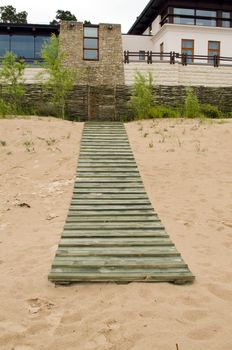 Seaside wooden plank path to house and weaven wooden fence.