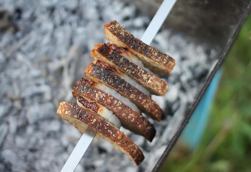 Grilling meat and bread on skewer over the brazier.
