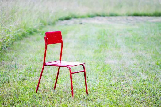 Red chair on green meadow om green mown grass background.