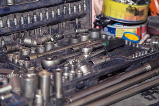 A set of wrenches and screwdrivers in a case on the table of a car mechanic. In the garage, a man changes parts on a vehicle. Small business concept, car repair and maintenance service. UHD 4K.