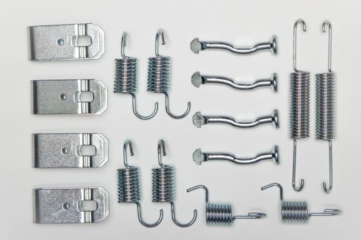 Repair kit for brakes, several metal springs, pins, limiters - clamps. Set of spare parts for car brake repair. Details on white background, copy space available. UHD 4K.