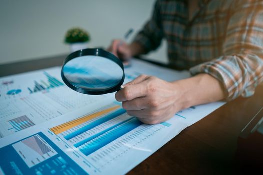 Businessman or Auditor Hand Looking At Tax Fraud Investigation, accounting records, financial statement, Internal audit, Through Magnifying Glass. Audit Concept.