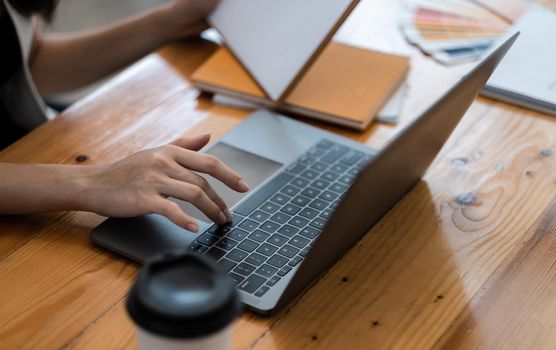 Closeup image of a business woman's hands working and typing on laptop computer keyboardat coffee shop.