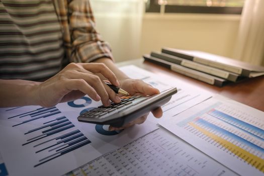 Close up of businesswoman or accountant using calculator for do math finance, Dedicated to the progress and growth of the company, investment statistical data, Financial and tax systems concept.