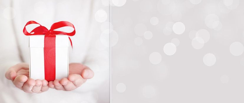 Gift box in wrapping paper with satin ribbon. Merry Christmas holiday concept.