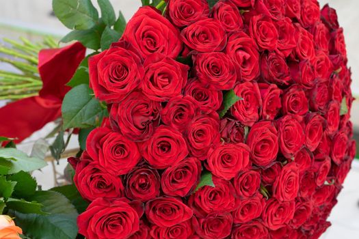 A large bouquet of red roses tied with a red ribbon. Close up
