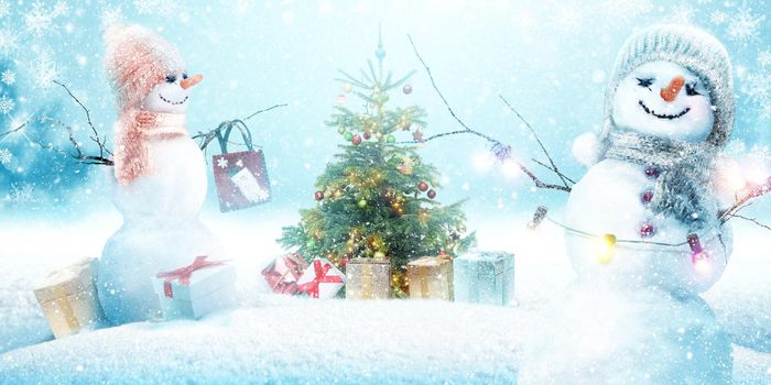 Happy snowman standing in winter christmas landscape.