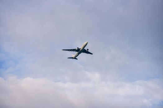 Passenger airplane flying against the cloudy sky.