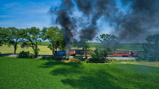 Ronks, Pennsylvania, June 2019 - Aerial View of Thomas the Tank Engine Approaching Pulling Passenger Cars Blowing Smoke on a Beautiful Sunny Day