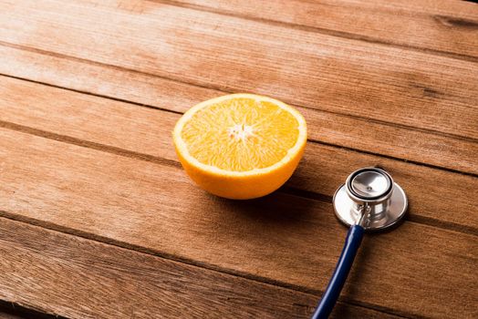 Orange fruit and Doctor stethoscope on wooden table, Vitamin C, Healthy lifestyle diet food concept