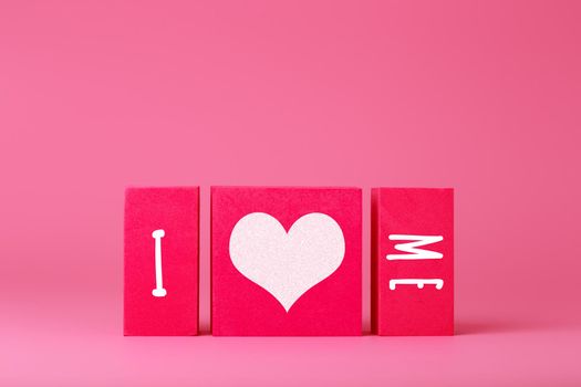 Trendy minimal I love me creative concept of self love and mental health or being single. Red blocks against pink background with copy space