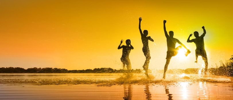 Group of young people playing games on sandy beach on a summer day.