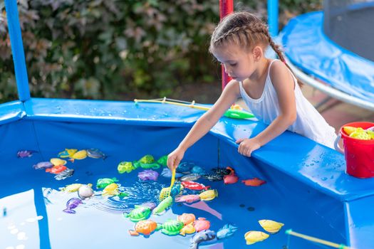 Child Fisher Catching Plastic Toy Fish On Pool Amusement Park Summer Day Little Girl Have Fun On Fishing Carnival Festival Entertainment For Children