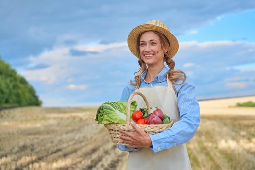 Woman farmer straw hat holding basket vegetable onion tomato salad cucumber standing farmland smiling Female agronomist specialist farming agribusiness Happy Girl dressed apron cultivated wheat field
