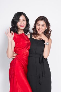 Two fashionable women in nice dresses standing together and having fun